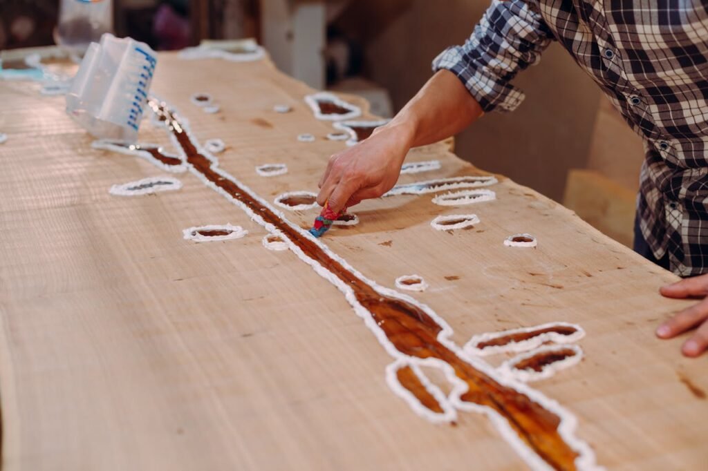 furniture upholstery A skilled craftsman applying resin on a wooden table in a workshop setting.